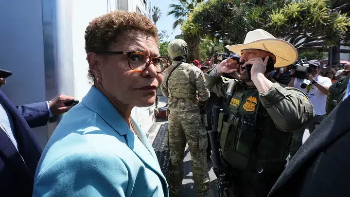 ICE Raid at MacArthur Park Sparks Backlash in L.A. 2 L.A. Mayor Karen Bass stands in front of a U.S. Border Patrol federal agent at MacArthur Park on Monday in Los Angeles. (Image Credit: Damian Dovarganes/AP)
